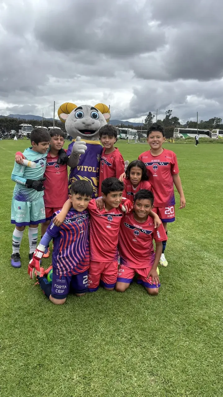 Niños de una categoría menor posando con una de las mascotas del torneo